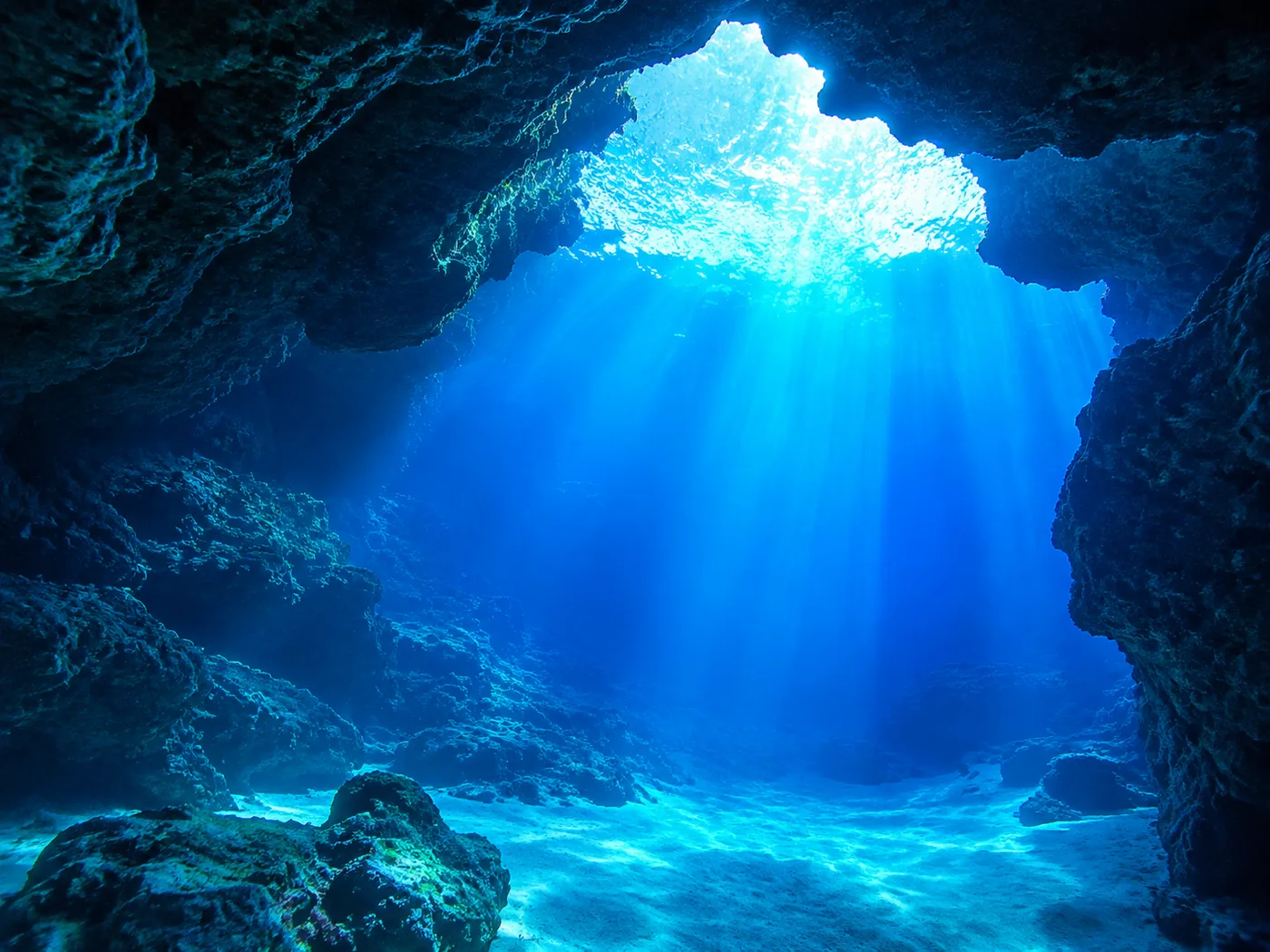 The blue light inside the cave arrives through a second, much larger opening below the waterline