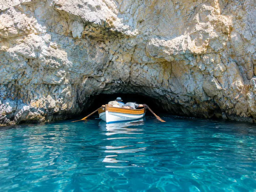 The low cave mouth at the waterline, about a metre high, with a rowboat lining up for it